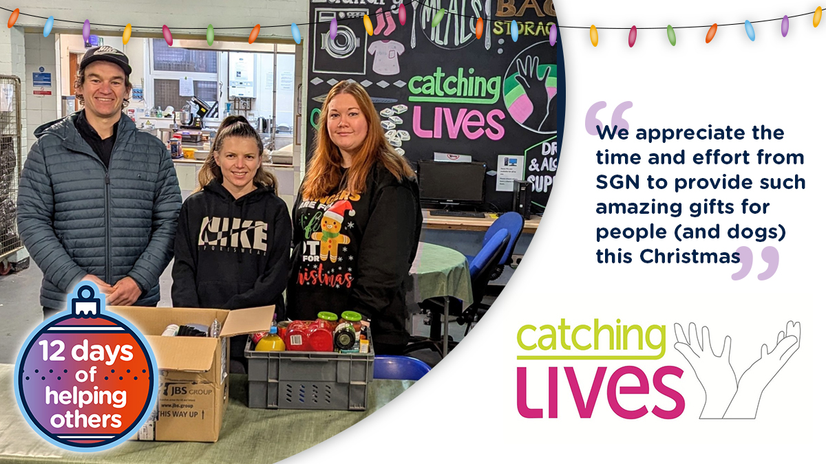 Three people stood behind a table filled with donations of food.