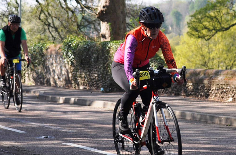 Carolina Karlstrom cycling on a road with countryside behind her