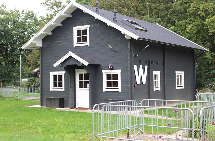 A grey house with fencing in front of it 