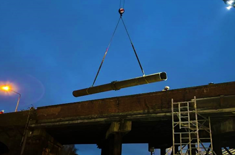 A section of pipe hanging in mid-air over a bridge at night