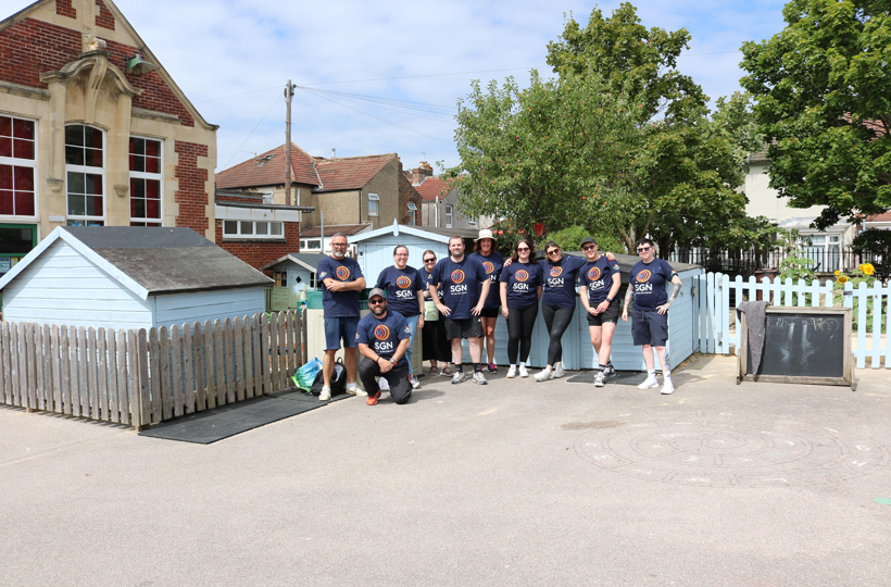 A group of people in SGN t-shirts in a primary school playground on a sunny day