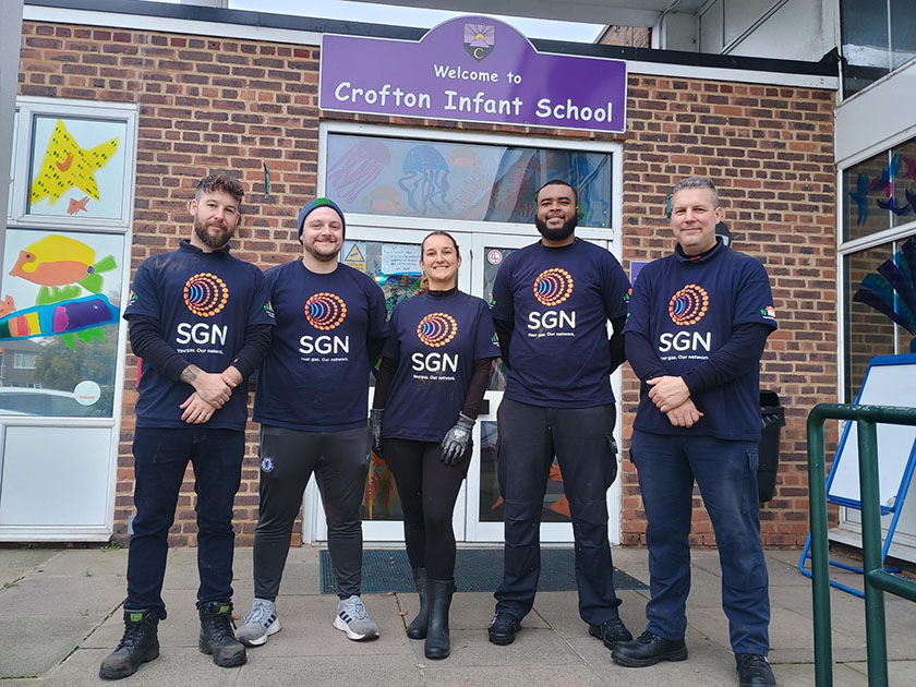 Five colleagues from London Construction stand in front of Crofton Infant School sign