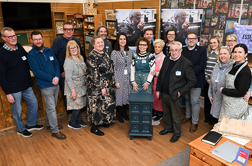 A large group of people smiling in a Sue Ryder charity shop