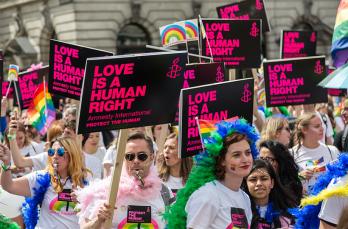 A Pride march with a variety of people holding placards that read 'Love is a human right'