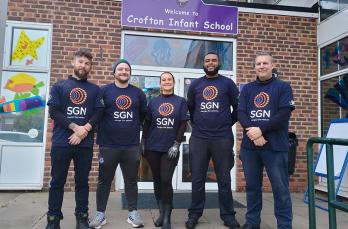 Five colleagues from London Construction stand in front of Crofton Infant School sign